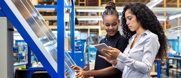 Female engineer showing the production plan to a worker on her digital tablet. Supervisor and female worker looking at digital tablet and discussing work in factory shop floor.