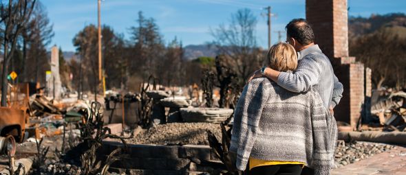 Couple looking at the damage done to their home and yard after a fire.